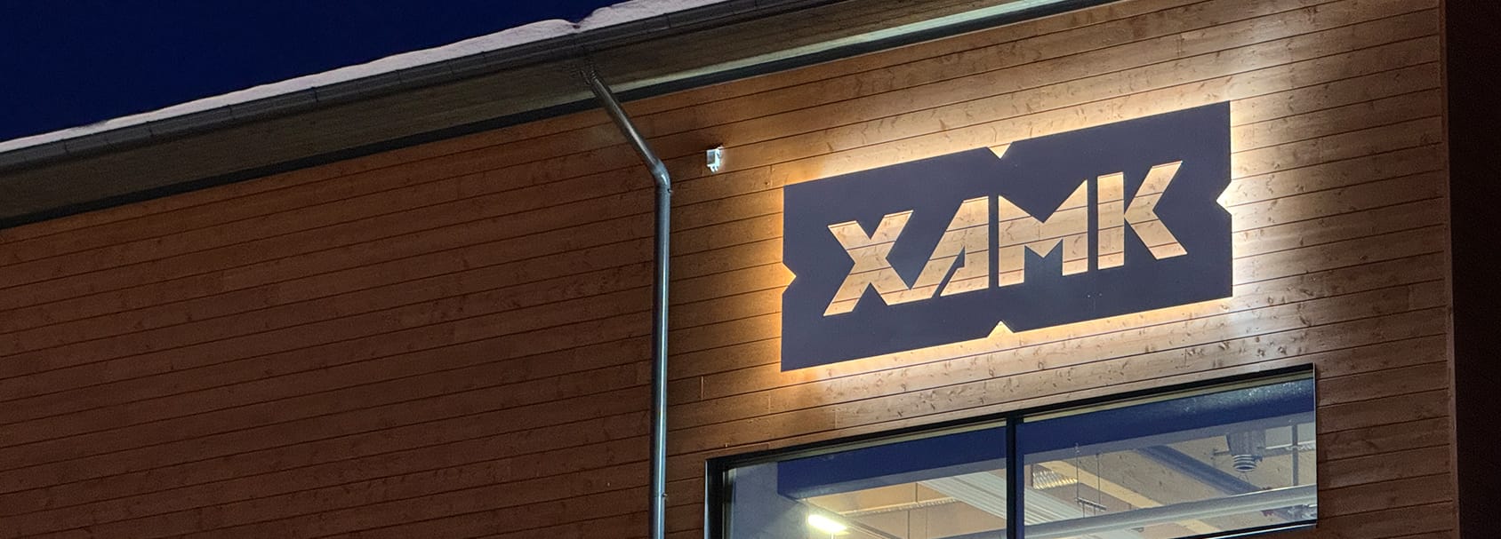 Lähikuva rakennuksen seinästä, jossa XAMK-logo. Xamk Teollisen puurakentamisen laboratorio Savonlinnassa.