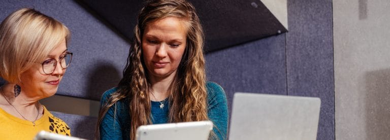 Kaksi henkilöä tarkastelee tietokoneen näytöltä asioita.