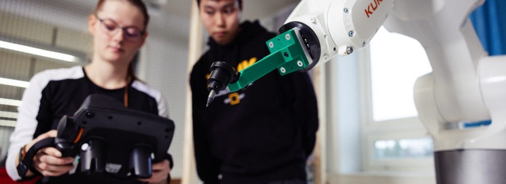 Kaksi opiskelijaa tutkii robottia.