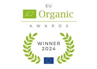 Kuvassa vihreäpohjainen kuva, jossa valkoisina pisteinä lehden reunaviivat. Tekstit EU Organic AWARDS WINNER 2024 ja alhaakka sini-keltainen EU:n lippu, josta lähtee lehtivanat kohti kuvan keskustaa.