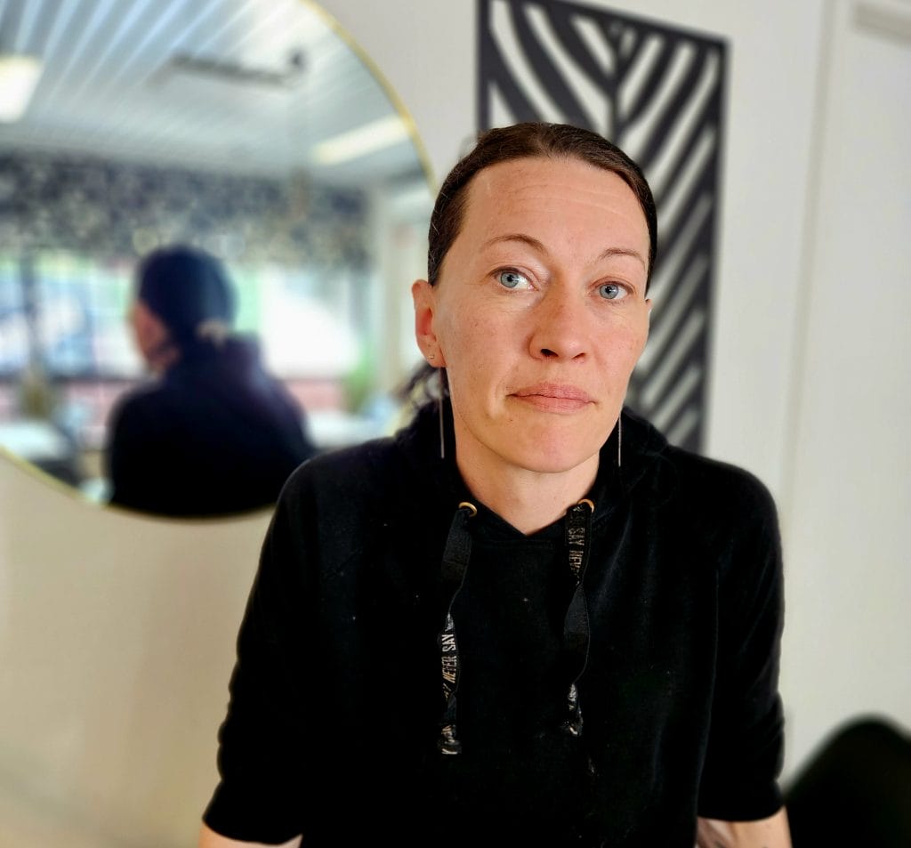 Henkilökuva tummahiuksisesta ihmisiestä, jolla on päällään musta pitkähihainen paita. Taustalla peili.