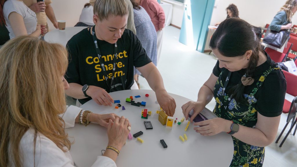 participants of the staff academy building Legos on the table. 