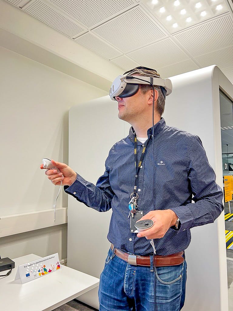 Henkilö käyttää VR-laseja ja pitää kädessä ohjaimia.