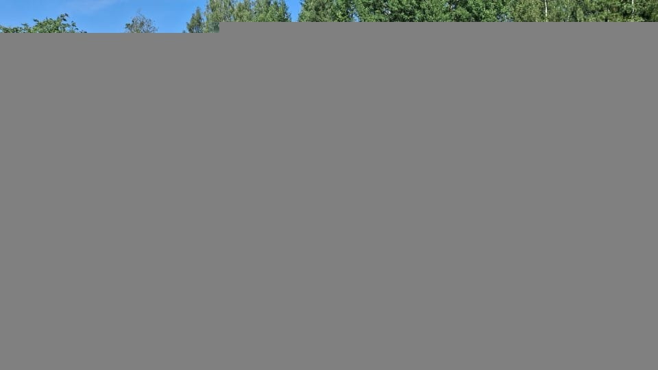 Ympäristöä, jossa rakennuksia ja ihminen, jolla on huomioliivi ja kypärä.