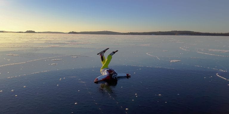 Luistelija selällään järven jäällä.