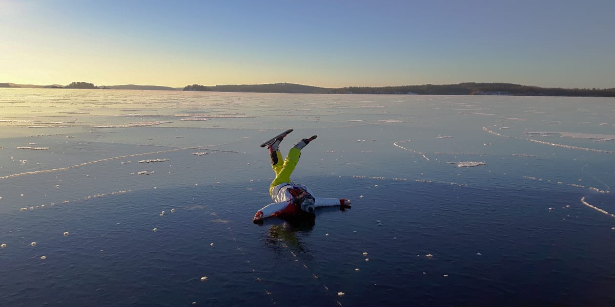 Luistelija selällään järven jäällä.