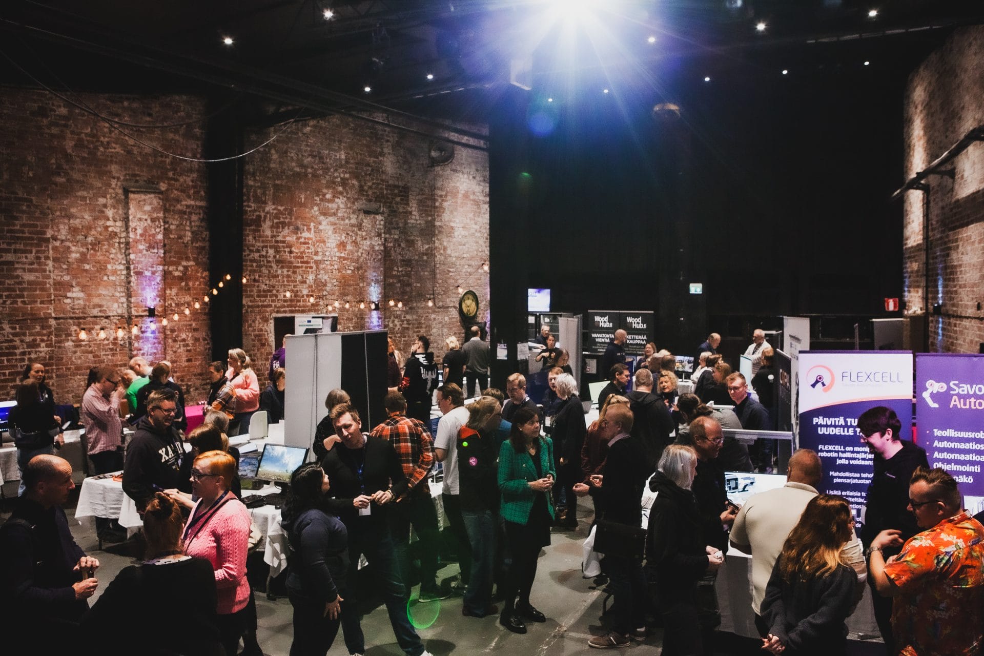 Ihmisiä kokoontumassa messuosastoilla.