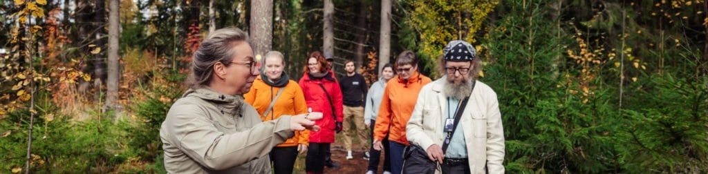 Ihmisiä kävelyllä metsässä.