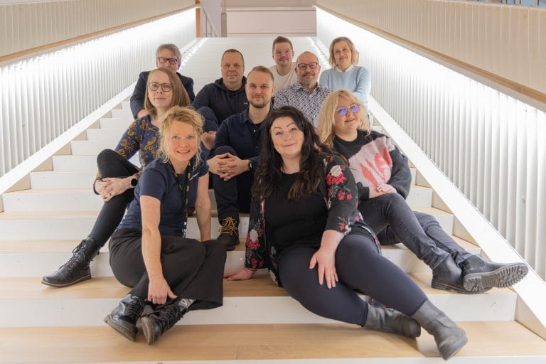 KAKE-tiimi istuu portailla, 10 henkilöä, vaalea moderni valaistus.