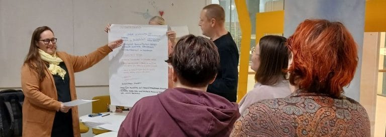 Ihmisiä fläppitaulun äärellä.