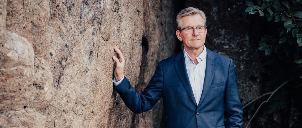 Vararehtori Kalevi Niemi seisoo ja nojaa kiviseinään