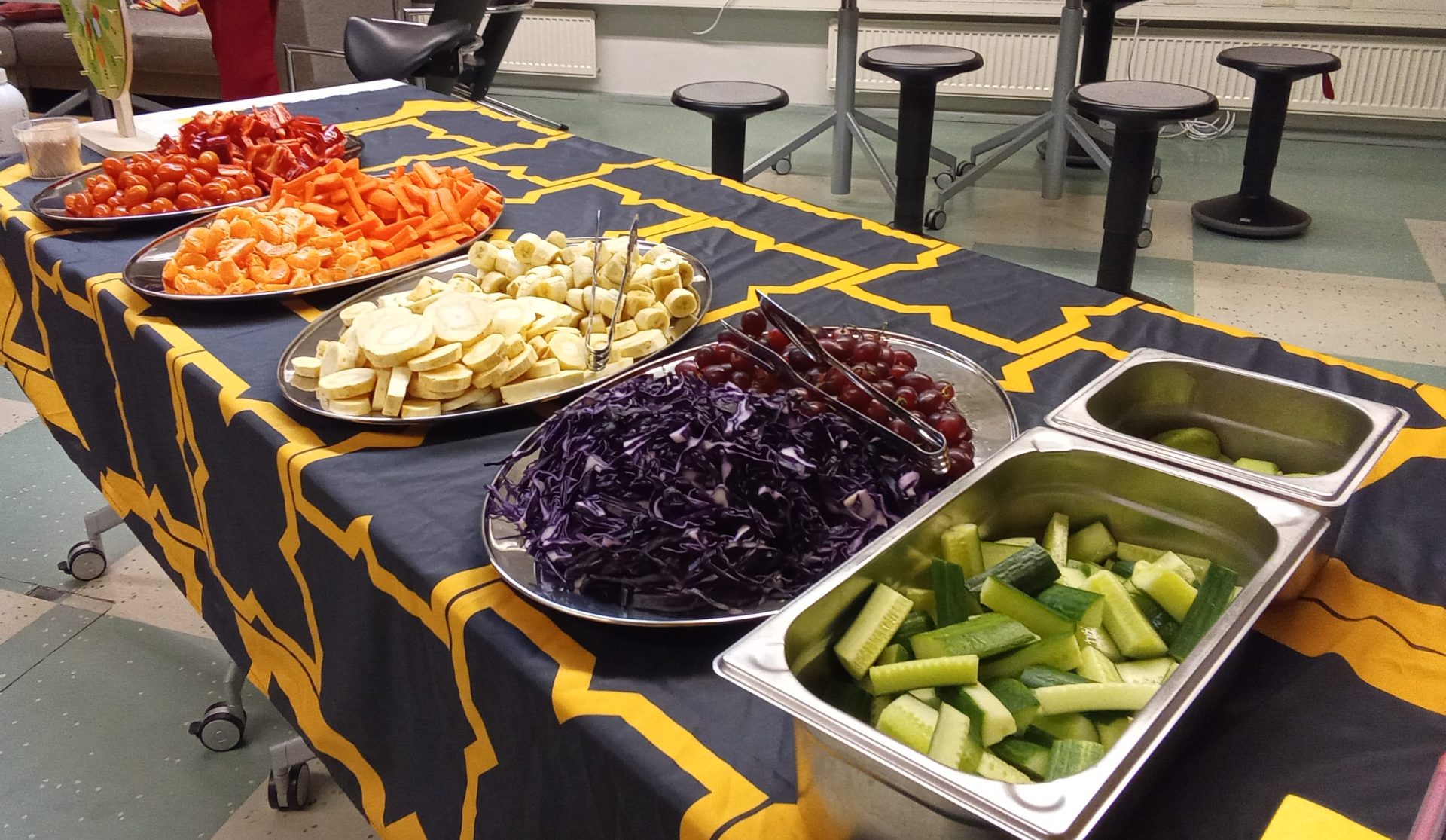 Kasviksia väriryhmissä tarjottimilla pöydän päällä.