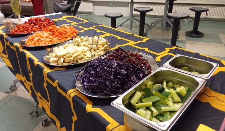 Kasviksia väriryhmissä tarjottimilla pöydän päällä.