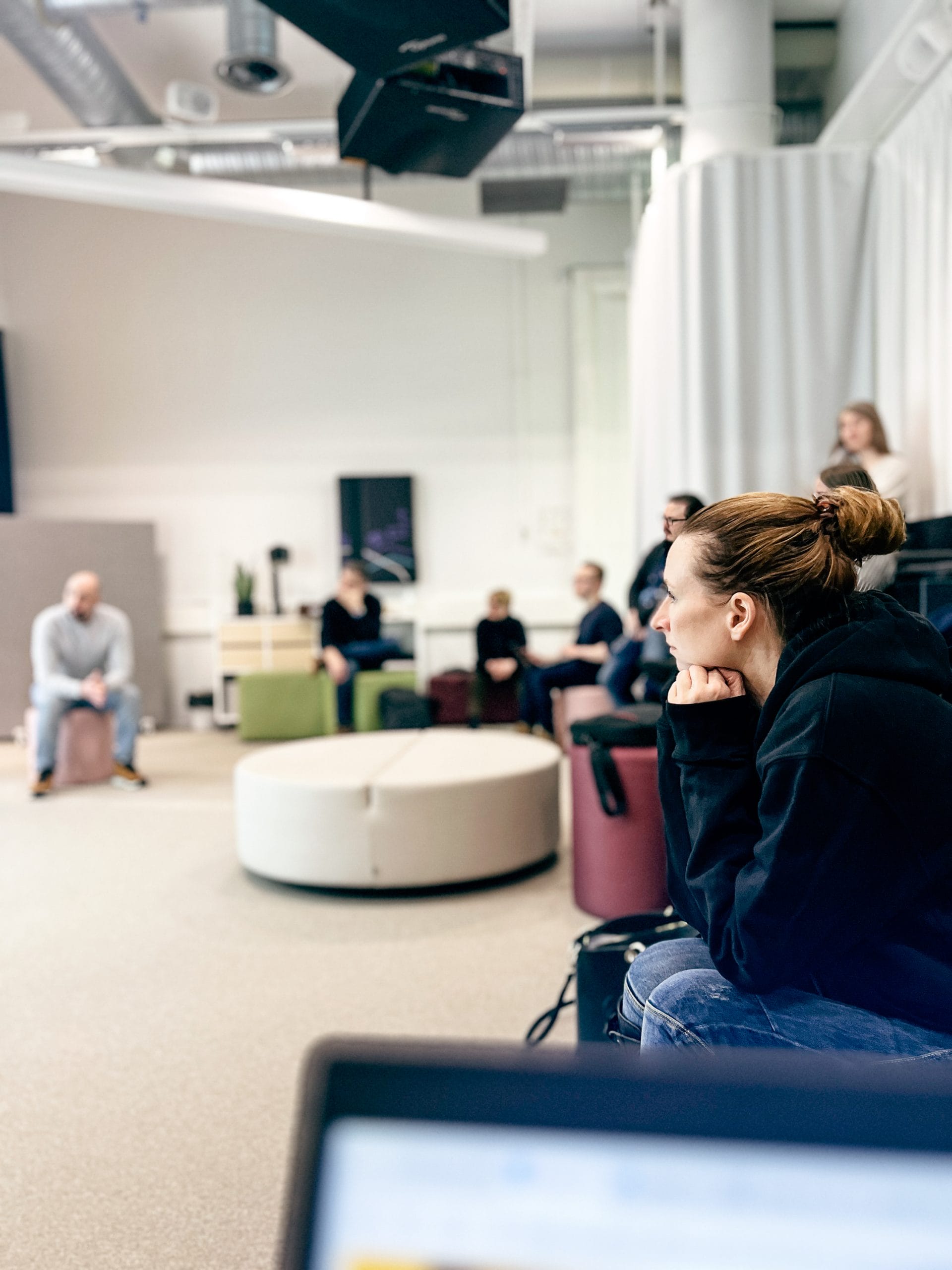 Ihmisiä istumassa Kouvolan Fuel-tilan katsomossa. Henkilö etualalla nojaa käsiin ja katsoo esitystä.