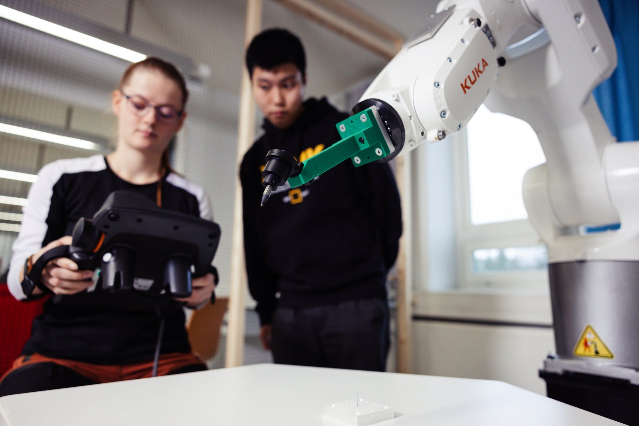 Henkilö ohjaamassa Robottia ja toinen henkilö seuraa vierestä.
