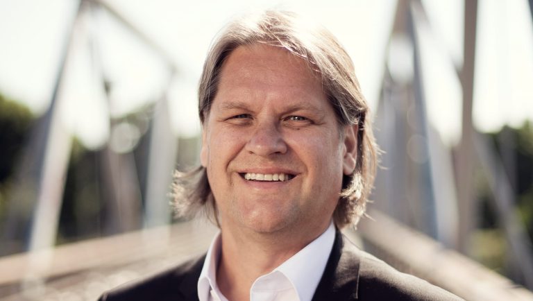 Hymyilevä henkilö ulkona.