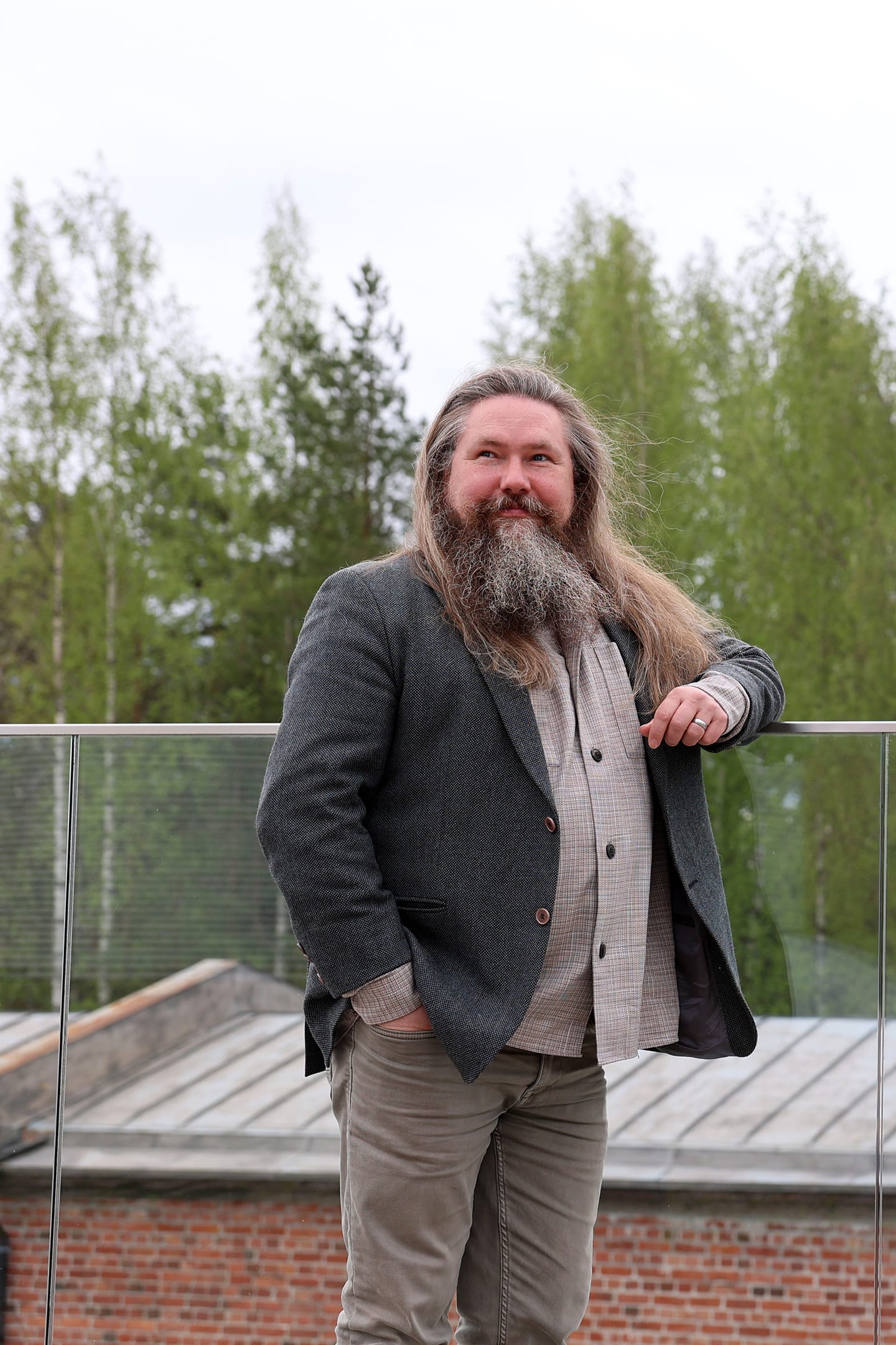 Henkilö ulkona, keväisiä puita takana.