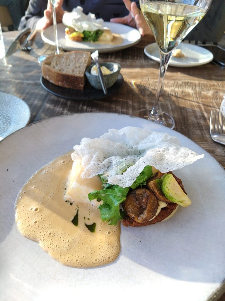 Ravintolapöydän kattaus. Lautasella annos, viinilasit.