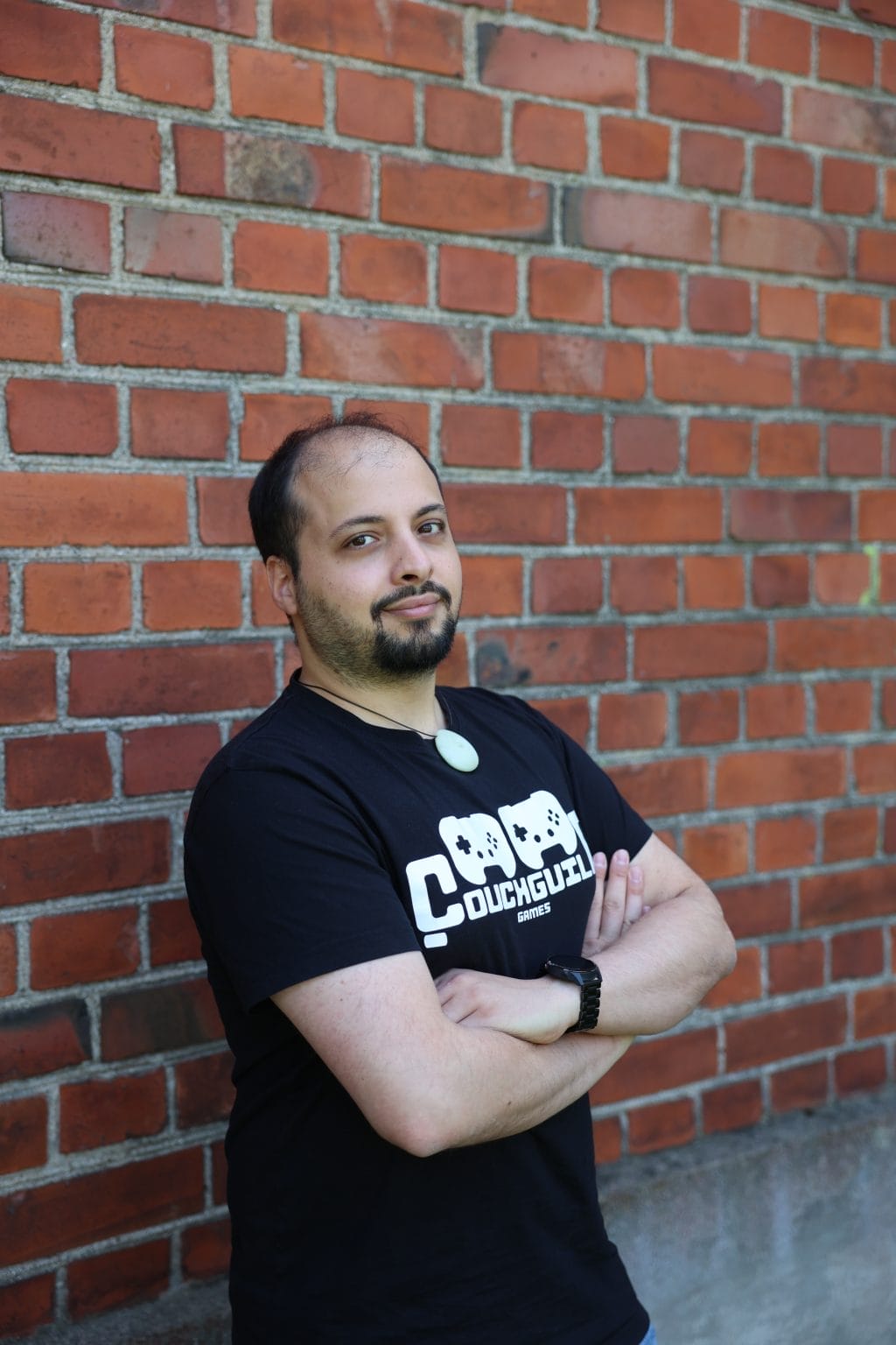 Game Design student standing with arms crossed in front of a red brick wall.
