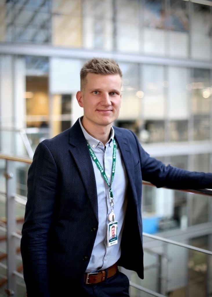 Teemu Halme seisoo toimistorakennuksen sisätiloissa työympäristössään.