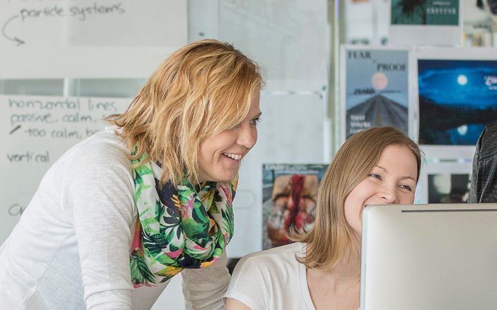 Opettaja opettaa kahta naista tietokoneen ääressä.