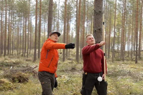 Miesopettaja ohjaa metsätalouden miesopiskelijaa mittaustehtävässä metsässä.