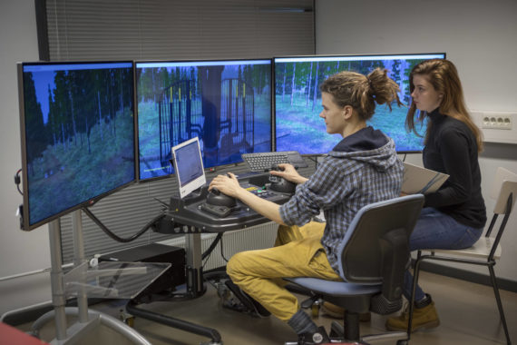 Nuori mies ja nainen metsätalouden simulaattoria käyttämässä.