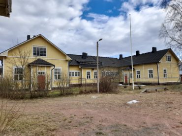 Kuvassa Tiutisen koulurakennus, suuri keltainen puutalo, ei enää koulukäytössä.